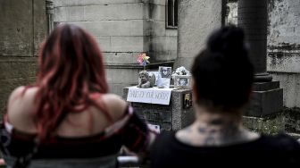 Orang-orang berkumpul di dekat makam pentolan The Doors Jim Morrison untuk memperingati 50 tahun kematiannya di pemakaman Pere Lachaise, Paris, pada (3/7/2021). [Martin BUREAU / AFP]