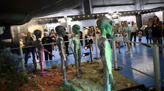 Orang-orang mengambil gambar pameran di Museum dan Pusat Penelitian UFO Internasional selama Festival UFO di Roswell, New Mexico, pada (2/7/2021). [Patrick T. FALLON / AFP]