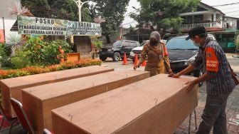 Lurah Kayu Putih, Artika Ristiana mengecek peti mati yang dibuat di Kantor Kelurahan Kayu Putih, Jakarta Timur, Selasa (6/7/2021). [Suara.com/Alfian Winanto]