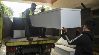 Pekerja mengangkut peti jenazah ke dalam truk untuk didistribusikan di TPU Petamburan, Jakarta Pusat, Selasa (6/7/2021). ANTARA FOTO/M Risyal Hidayat