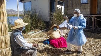 Petugas kesehatan berbincang dengan warga sebelum menyuntik dengan vaksin COVID-19 Sinopharm di Pulau Uros, Danau Titicaca, Puno, Peru, pada (7/7/2021). [Carlos MAMANI / AFP]