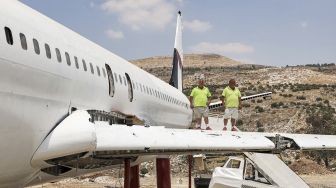 Saudara kembar Palestina Atallah dan Khamis al-Sairafi (60) berdiri bersama di sayap pesawat Boeing 707 yang diubah menjadi restoran yang mereka sebut "Restoran Maskapai Penerbangan Palestina-Yordania dan Kedai Kopi Al-Sairafi Nablus", di Kota Nablus, Palestina, pada (5/7/2021). [JAAFAR ASHTIYEH / AFP]