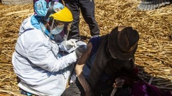 Petugas kesehatan menyuntik warga dengan vaksin COVID-19 Sinopharm di Pulau Uros, Danau Titicaca, Puno, Peru, pada (7/7/2021). [Carlos MAMANI / AFP]