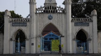 Warga melintas didepan pemberitahuan ditiadakan Shalat Jumat, di Masjid Agung Solo, Jawa Tengah, Jumat (9/7/2021). ANTARA FOTO/Maulana Surya