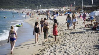 Orang-orang mengunjungi pantai Pampelonne setelah Prancis baru-baru ini melonggarkan tindakan pencegahan penyebaran COVID-19 di Ramatuelle, Saint-Tropez, Prancis, pada (10/7/2021). [CLEMENT MAHOUDEAU / AFP]