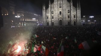 Pendukung tim sepak bola nasional Italia merayakan kemenangan setelah Italia mengalahkan Inggris pada final UEFA EURO 2020 di Piazza del Duomo, Milan pada (11/7/2021). [Marco BERTORELLO / AFP]