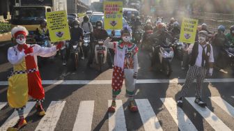 Angggota Komunitas Aku Badut Indonesia (ABI) melakukan aksi kampanye untuk menggunakan masker di kawasan Cilandak, Jakarta Selatan, Senin (12/7/2021). [Suara.com/Alfian Winanto]