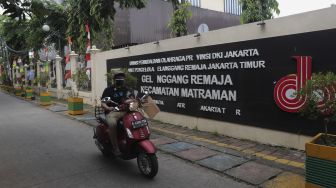 Pengendara sepeda motor melintas di depan GOR Kecamatan Matraman yang dijadikan tempat isolasi mandiri, di Jakarta, Selasa (13/7/2021). [Suara.com/Angga Budhiyanto]