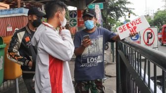 Warga membenarkan handphonenya di penyedia jasa servis handphone di Kawasan Pusat Grosir Cililitan (PGC), Jakarta Timur, Selasa (13/7/2021). [Suara.com/Alfian Winanto]