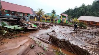 Beberapa warga berada di SD Negeri 07 Molawe dengan kondisi halaman sekolah dipenuhi material banjir bandang di Kecamatan Molawe, Konawe Utara, Sulawesi Tenggara, Senin (12/7/2021). ANTARA FOTO/Suyamin