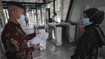 Petugas memeriksa surat tanda registrasi pekerja (STRP) calon penumpang di Halte Transjakarta Gelora Bung Karno, Jakarta, Rabu (14/7/2021). [Suara.com/Angga Budhiyanto]