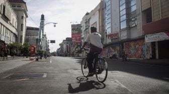 Seorang warga melintas di kawasan pertokoan Jalan Gatot Subroto yang sepi dari aktifitas dampak Pemberlakukan Pembatasan Kegiatan Masyarakat (PPKM) Darurat di Solo, Jawa Tengah, Rabu (14/7/2021).  ANTARA FOTO/Mohammad Ayudha