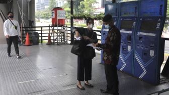 Petugas memeriksa surat tanda registrasi pekerja (STRP) calon penumpang di Halte Transjakarta Gelora Bung Karno, Jakarta, Rabu (14/7/2021). [Suara.com/Angga Budhiyanto]