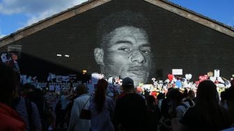 Pengunjuk rasa antirasisme berkumpul di depan mural Marcus Rashford yang menjadi sasaran vandalisme di Manchester, Inggris, pada 13 Juli 2021. [Photo/AFP]
