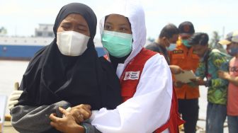 Seorang anggota keluarga dari korban kapal tenggelam menangis dalam pelukan petugas PMI usai menyaksikan jenazah kerabatnya yang berhasil ditemukan SAR, di dermaga Kesatuan Penjagaan Laut dan Pantai (KPLP) di Pontianak, Kalimantan Barat, Kamis (15/7/2021). [ANTARA FOTO/Jessica Helena Wuysang]