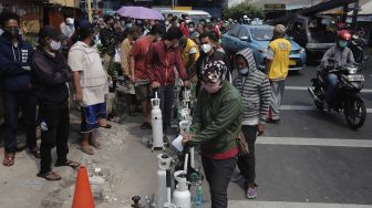 Sejumlah warga mengantre untuk mengisi ulang oksigen medis yang dibagikan secara gratis di kawasan Manggarai, Jakarta, Kamis (15/7/2021). [Suara.com/Angga Budhiyanto]