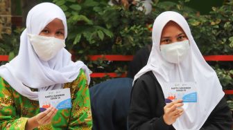 Dua orang pelajar menunjukkan sertifikat usai menjalani Covid-19 di SMA Negeri 38, Jakarta Selatan, Kamis (15/7/2021). [Suara.com/Alfian Winanto]