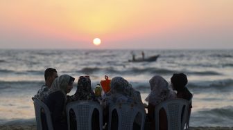 Warga menghabiskan waktu di pantai saat musim panas yang tinggi di Gaza, Palestina, pada (16/7/2021). [MOHAMMED ABED / AFP]