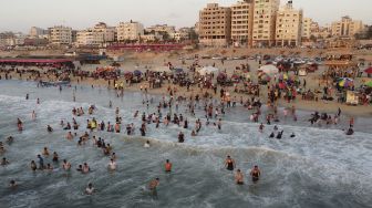 Foto udara warga berenang di Mediterania saat musim panas yang tinggi di Gaza, Palestina, pada (16/7/2021). [MOHAMMED ABED / AFP]