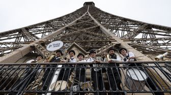 Pengunjung berpose dari lantai dua Menara Eiffel di Paris, Prancis, pada (16/7/2021). [Bertrand GUAY / AFP]