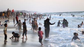 Warga menghabiskan waktu di pantai saat musim panas yang tinggi di Gaza, Palestina, pada (16/7/2021). [MOHAMMED ABED / AFP]