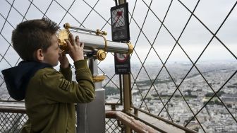 Seorang anak menikmati pemandangan dari lantai dua Menara Eiffel di Paris, Prancis, pada (16/7/2021). [Bertrand GUAY / AFP]