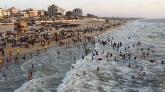 Foto udara warga berenang di Mediterania saat musim panas yang tinggi di Gaza, Palestina, pada (16/7/2021). [MOHAMMED ABED / AFP]