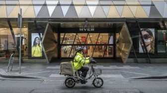 Seorang pengirim makanan melintas di Melbourne Central Business District, Melbourne, Australia, pada (16/7/2021). [ASANKA BRENDON RATNAYAKE / AFP]