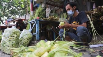 Pedagang membuat kulit ketupat di Pasar Palmerah, Jakarta Pusat, Minggu (18/7/2021). [Suara.com/Alfian Winanto]