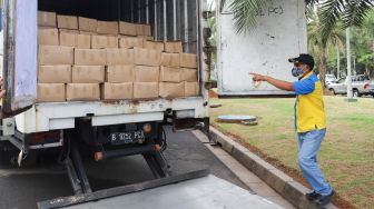 Petugas menaruh paket bantuan ke dalam truk di Lapangan Monumen Nasional (Monas), Jakarta Pusat, Senin (19/7/2021). [Suara.com/Alfian Winanto]