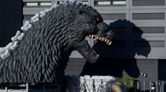 Dua warga memotret patung Godzilla di kota Shinjuku, Tokyo, Jepang, Minggu (18/7/2021).  ANTARA FOTO/Sigid Kurniawan

