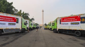 Deretan truk yang membawa bantuan kemanusiaan untuk warga yang menjalani Isoman Covid-19 terparkir di Lapangan Monumen Nasional (Monas), Jakarta Pusat, Senin (19/7/2021). [Suara.com/Alfian Winanto]