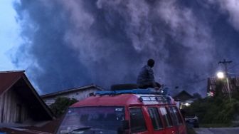 Warga mengamati Gunung Sinabung yang menyemburkan material vulkanik di Desa Kutarayat, Naman Teran, Karo, Sumatera Utara, Senin (19/7/2021). ANTARA FOTO/Sastrwawan Ginting
