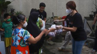 Pedangdut Dewi Perssik dan Lucinta Luna membagikan paket bantuan berupa daging kurban dan sembako kepada warga di sekitar rumahnya di Kawasan Fatmawati, Jakarta Selatan, Selasa (20/7/2021). [Suara.com/Alfian Winanto]