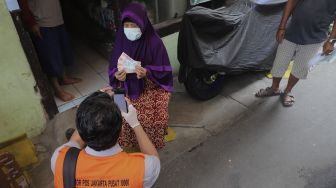 Petugas Pos menyalurkan Bantuan Sosial Tunai (BST) dari rumah ke rumah di kawasan Petojo Selatan, Gambir, Jakarta, Rabu (21/7/2021). [Suara.com/Angga Budhiyanto]