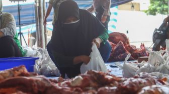 Petugas membungkus daging hewan kurban di Masjid Agung Al Azhar, Jakarta Selatan, Rabu (21/7/2021). [Suara.com/Alfian Winanto]