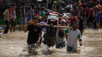 Warga membantu menyeberangkan speda motor yang terjebak banjir di ruas jalan nasional Jeruklegi-Kawunganten, di Desa Jeruklegi Wetan, Jeruklegi, Cilacap, Jawa Tengah, Rabu (21/7/2021). ANTARA FOTO/Idhad Zakaria