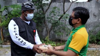 Warga muslim (kanan) memberikan daging kurban kepada seorang Pecalang atau petugas keamanan adat Bali pada Hari Raya Idul Adha 1442 H di kawasan Padangsambian, Denpasar, Bali, Selasa (20/7/2021). ANTARA FOT