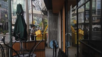 Pekerja beraktivitas di dekat restoran yang tutup di kawasan Melawai, Jakarta, Rabu (21/7/2021). [Suara.com/Angga Budhiyanto]