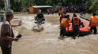 Petugas SAR gabungan menyeberangkan warga menggunakan perahu karet di ruas jalan nasional Jeruklegi-Kawunganten, yang terputus akibat banjir di Desa Jeruklegi Wetan, Jeruklegi, Cilacap, Jawa Tengah, Rabu (21/7/2021). ANTARA FOTO/Idhad Zakaria