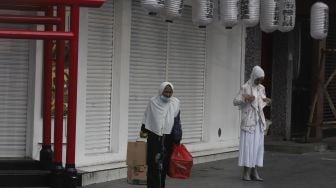 Warga berjalan di depan restoran yang tutup di kawasan Melawai, Jakarta, Rabu (21/7/2021). [Suara.com/Angga Budhiyanto]