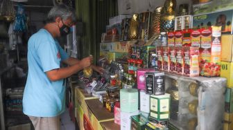 Penjual membersihkan barang oleh-oleh khas haji di sekitar kawasan Asrama Haji, Pondok Gede, Jakarta Timur, Kamis (22/7/2021). [Suara.com/Alfian Winanto]