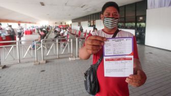 Warga menunjukkan sertifikat vaksin usai menjalani vaksinasi covid-19 di Terminal Kampung Rambutan, Jakarta Timur, Kamis (22/7/2021). [Suara.com/Alfian Winanto]