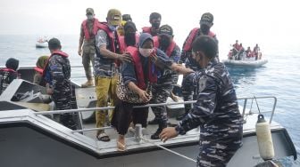 Prajurit TNI AL membantu warga naik ke ke haluan KRI Teluk Youtefa-522 yang lego jangkar saat Operasi Serbuan Vaksinasi Masyarakat Maritim di Perairan Kepulauan Seribu, Jakarta, Jumat (23/7/2021). ANTARA FOTO/M Risyal Hidayat