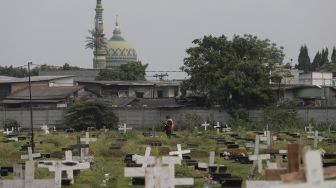 Warga berjalan usai melayat ke makam keluarganya yang meninggal dunia karena COVID-19 di TPU Tegal Alur, Jakarta, Jumat (23/7/2021). [Suara.com/Angga Budhiyanto]