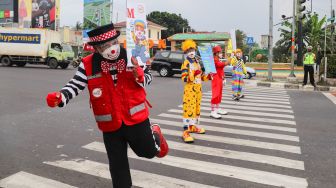 Angggota Komunitas Aku Badut Indonesia (ABI) melakukan aksi kampanye untuk mengajak masyarakat melakukan vaksinasi dan mematuhi protokol kesehatan di Kawasan Juanda, Depok, Jawa Barat, Jumat (23/7/2021). [Suara.com/Alfian Winanto]