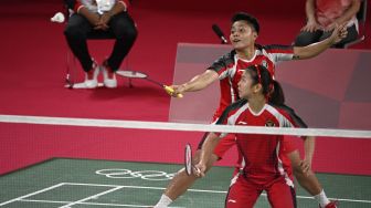 Atlet Indonesia Apriyani Rahayu (belakang) melakukan pukulan dalam pertandingan penyisihan grup bulu tangkis ganda putri dengan pasangan Indonesia Greysia Polii (depan) melawan Lee Meng Yean dan Chow Mei Kuan dari Malaysia selama Olimpiade Tokyo 2020 di Musashino Forest Sports Plaza, Tokyo, Sabtu (24/7/2021). [Alexander NEMENOV / AFP]