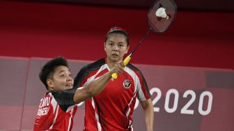 Greysia Polii (kanan) menyaksikan Apriyani Rahayu dari Indonesia melakukan pukulan dalam pertandingan penyisihan grup bulu tangkis ganda putri melawan Lee Meng Yean dan Chow Mei Kuan dari Malaysia selama Olimpiade Tokyo 2020 di Musashino Forest Sports Plaza, Tokyo, Sabtu (24/7/2021). [Alexander NEMENOV / AFP]