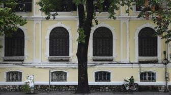 Seorang pengemudi pengiriman Grab duduk sendirian di sepanjang jalan yang hampir kosong di Hanoi, Vietnam, Sabtu (24/7/2021). [Manan VATSYAYANA / AFP]