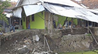 Warga melihat kondisi rumah yang rusak akibat longsor di Desa Kertasmaya, Indramayu, Jawa Barat, Sabtu (24/7/2021). [ANTARA FOTO/Dedhez Anggara]